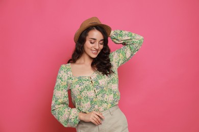 Beautiful young woman with straw hat on pink background