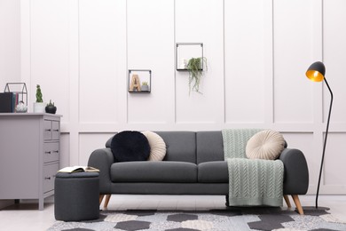 Photo of Stylish living room interior with comfortable grey sofa and lamp