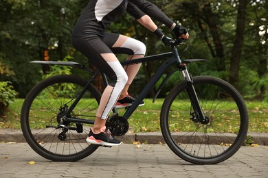 Young woman riding bicycle on road outdoors, closeup