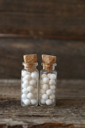 Bottles with homeopathic remedy on wooden table, closeup. Space for text