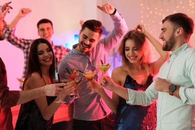 Group of young people holding martini cocktails at party