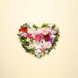 Beautiful heart made of different flowers on beige background, top view