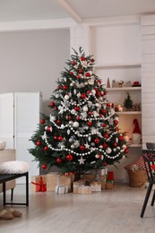 Beautifully decorated Christmas tree and gift boxes in room. Interior design