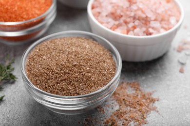 Different kinds of salt on grey table, closeup