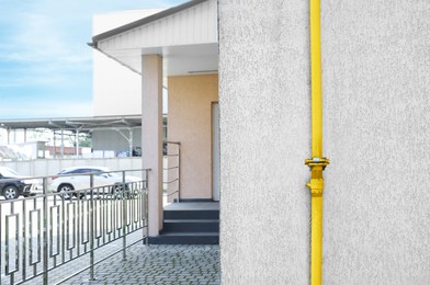 Photo of Yellow gas pipe near beige wall outdoors, space for text