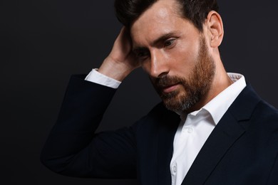 Photo of Handsome bearded man looking down on black background