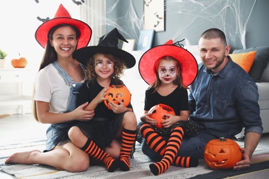 Happy family with Halloween candy buckets and pumpkin head jack lantern at home