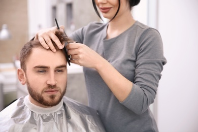 Professional female hairdresser working with client in salon