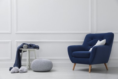 Photo of Stylish room interior with pouf and armchair. Space for text