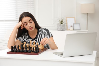 Unhappy young woman playing chess with partner through online video chat at home