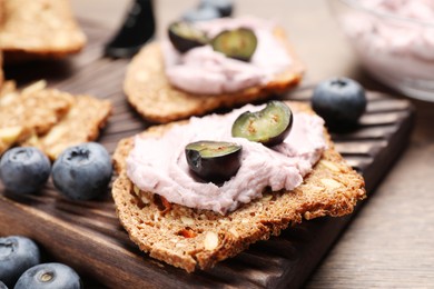 Tasty sandwiches with cream cheese and blueberries on wooden table, closeup