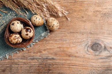 Flat lay composition with quail eggs on wooden table. Space for text