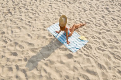 Woman sunbathing on beach towel at sandy coast