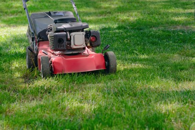 Modern garden lawn mower cutting green grass outdoors