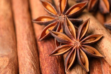 Aromatic anise stars on cinnamon sticks as background, closeup