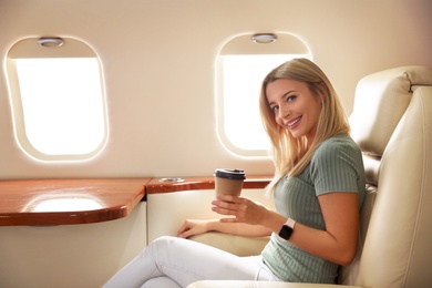 Beautiful woman with paper cup on plane. Air travel