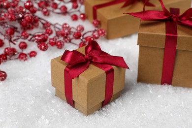 Gift boxes and decorative branches on artificial snow, closeup. Christmas celebration