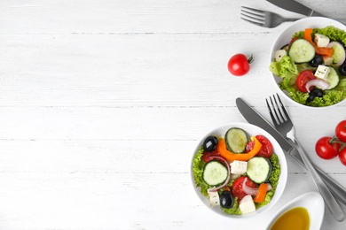 Tasty fresh Greek salad on white wooden table, flat lay. Space for text