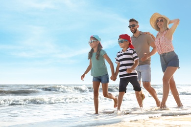 Photo of Happy family running on sandy beach near sea