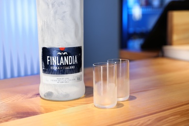 Photo of MYKOLAIV, UKRAINE - SEPTEMBER 23, 2019: Finlandia vodka and shot glasses on wooden bar counter