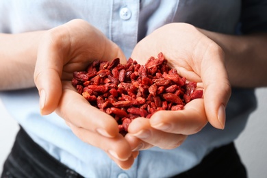 Woman holding red dried goji berries, closeup