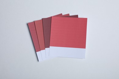 Photo of Color sample cards of red shades on light background, top view
