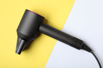 Hair dryer on color background, top view. Professional hairdresser tool