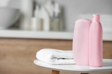 Shampoo, conditioner and towel on white table in bathroom, space for text