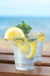 Refreshing water with lemon and mint on wooden table outdoors