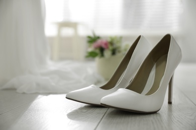 Pair of white high heel shoes and blurred wedding dress on background, space for text