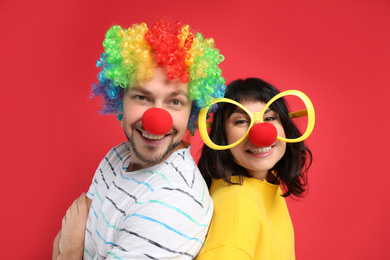 Couple with funny accessories on red background. April fool's day