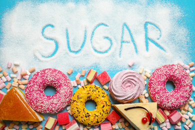 Photo of Flat lay composition with sweets and word SUGAR on light blue background