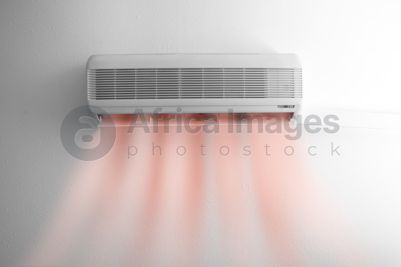 Modern conditioner and illustration of warm air flow on white wall indoors