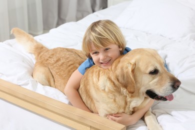 Photo of Cute little child with Golden Retriever on bed. Adorable pet