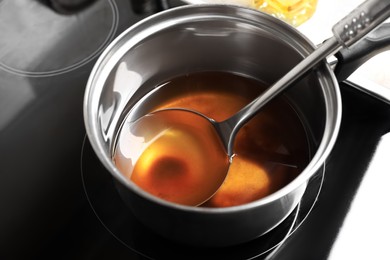 Photo of Saucepan and ladle with used cooking oil on stove, closeup