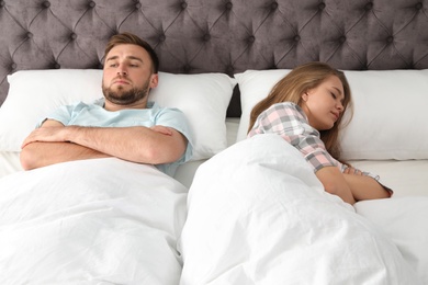 Young couple with relationship problems in bed at home