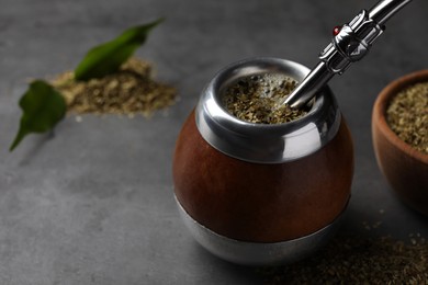 Photo of Calabash with mate tea and bombilla on light grey table, closeup. Space for text