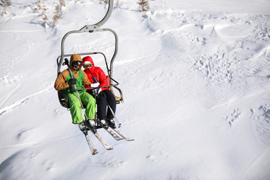 People using chairlift at mountain ski resort, space for text. Winter vacation