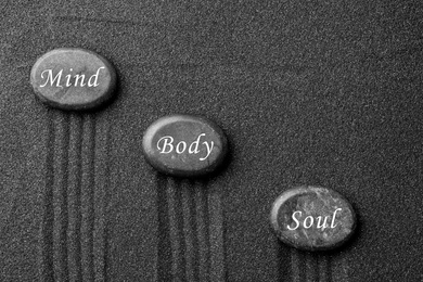Stones with words Mind, Body, Soul on sand, flat lay. Zen and harmony 