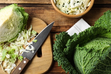 Photo of Whole and cut fresh savoy cabbages on wooden table, flat lay