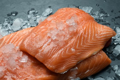 Photo of Fresh raw salmon with ice on black table, closeup