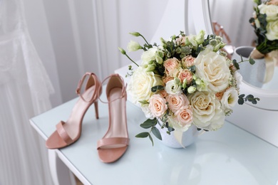 Beautiful wedding bouquet and shoes on dressing table indoors