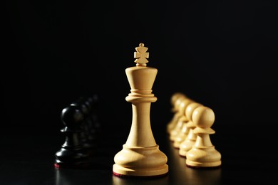 Photo of Wooden king, white and black chess pieces against dark background. Competition concept
