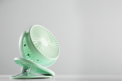 Portable fan on table against light grey background, space for text. Summer heat