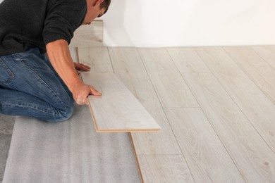 Professional worker installing new laminate flooring, closeup. Space for text