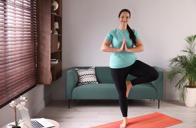 Overweight woman practicing yoga at home, space for text