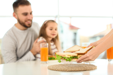 Photo of Happy family having breakfast with sandwiches in kitchen, closeup