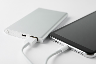 Photo of Smartphone charging with power bank on white background, closeup