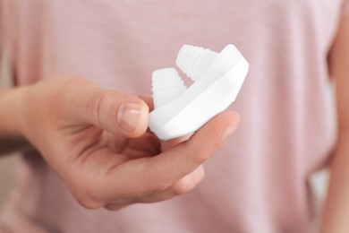 Woman holding anti-snoring device for nose, closeup