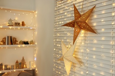 Beautiful decorative stars and festive lights in room. Christmas atmosphere